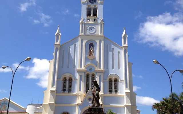 Igreja com torre e estátua na frente em Carmópolis de Minas